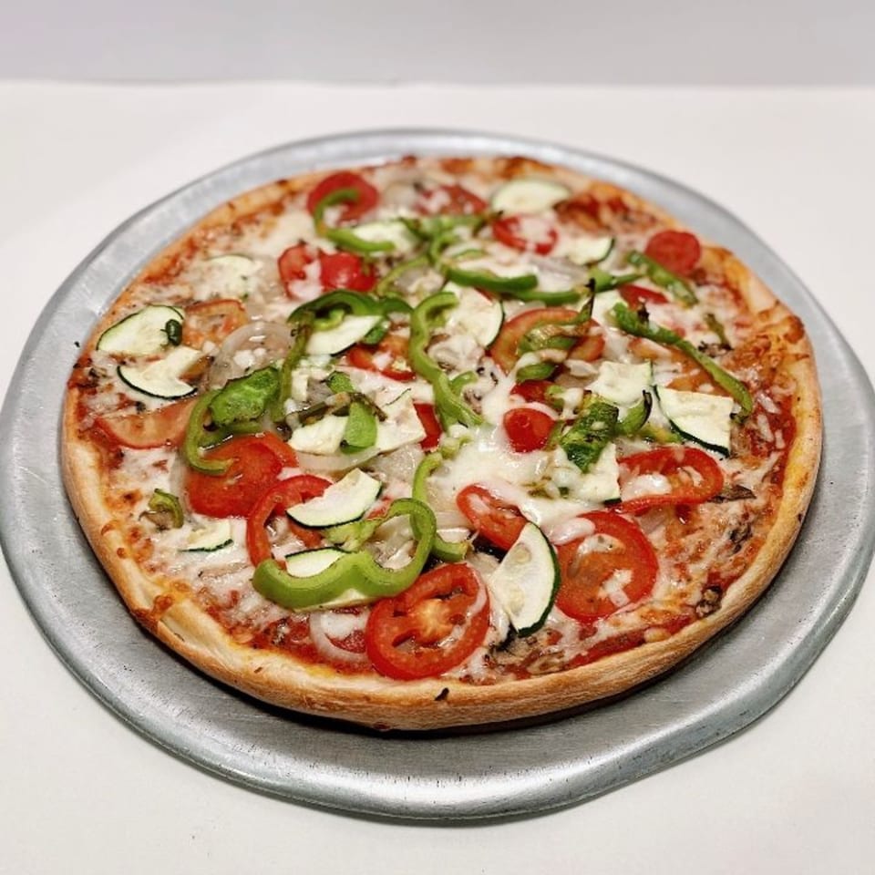 ZIPS' NY Pizza with tomatoes, zucchini, green peppers, and onions on a metal tray.