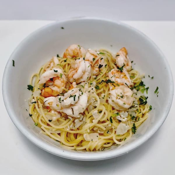 Shrimp scampi with spaghetti, garlic, and parsley in a white bowl from ZIPS' NY Pizza & Italian Kitchen.