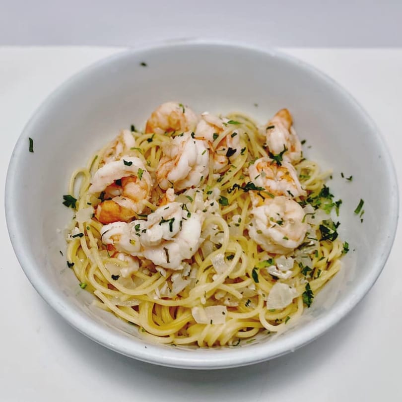 Shrimp scampi with spaghetti, garlic, and parsley in a white bowl from ZIPS' NY Pizza & Italian Kitchen.