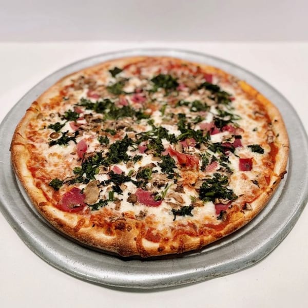 A ZIPS' NY Pizza with white sauce, spinach, mushrooms, and red meat on a metal pan.