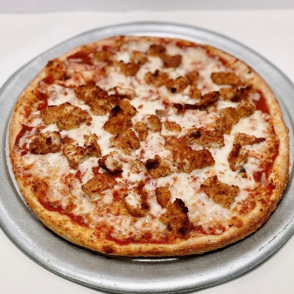 ZIPS' NY Pizza with crispy chicken pieces, melted mozzarella, and red sauce on a metal pan.